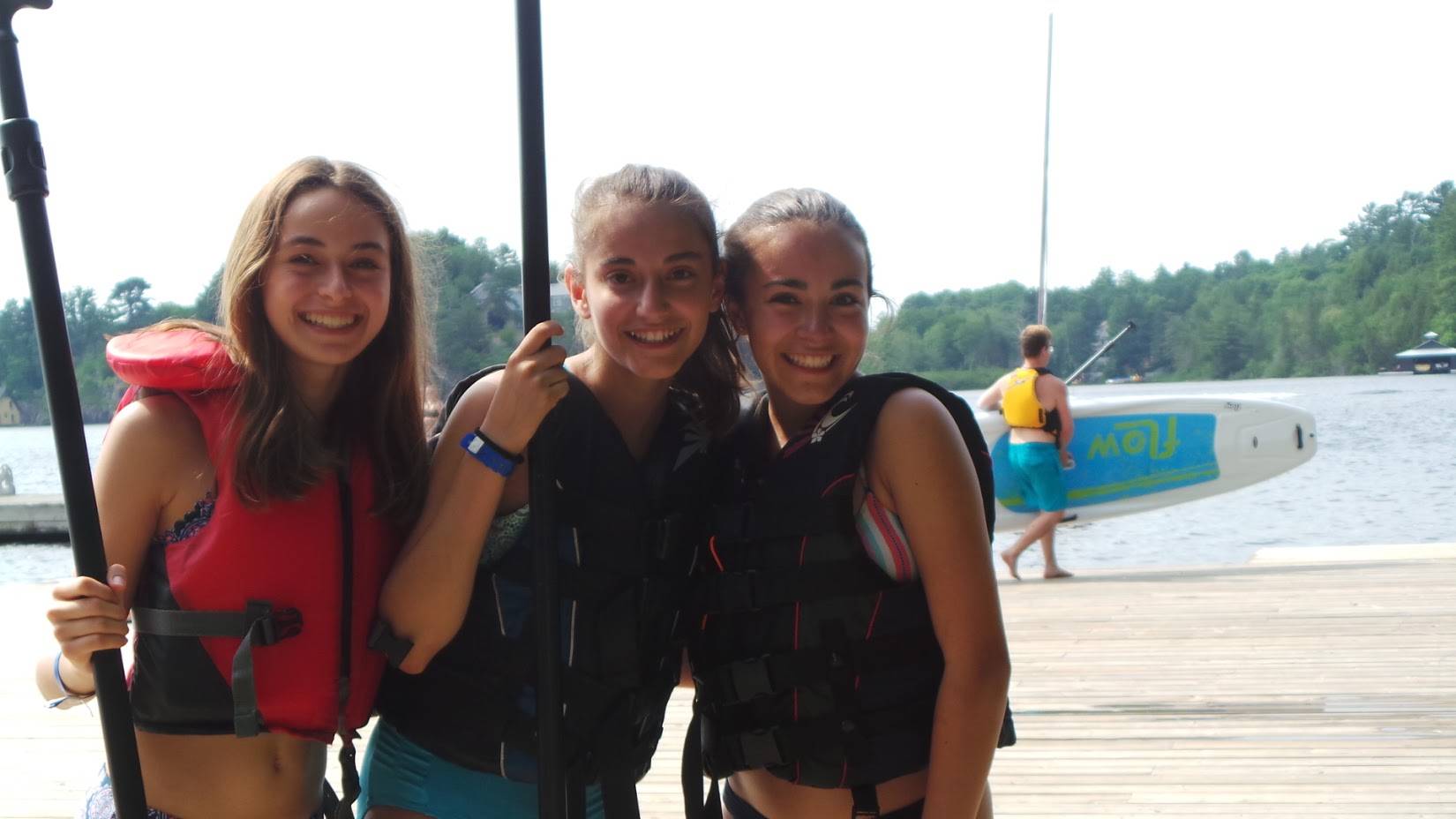 Amigas en el muelle con chalecos salvavidas