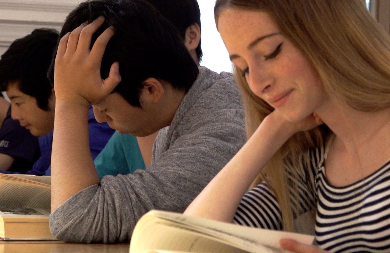 Alumnos concentrados leyendo en clase